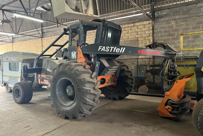 A large black tractor in a warehouse